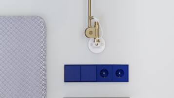 A wall-mounted lamp with a white shade and brass finish, a blue switchboard, and a black electrical panel.