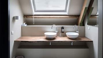 Een badkamer met twee wasbakken, een dakraam en houten balken.