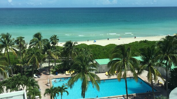 A pool area with a view of the beach and ocean.