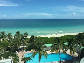 A pool area with a view of the beach and ocean.