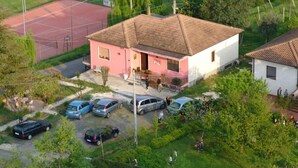 Zona residencial con una casa, cancha de tenis y coches estacionados.