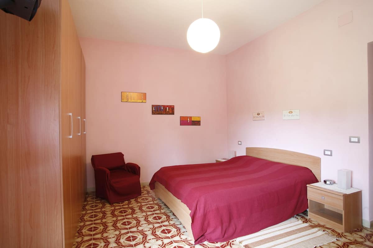 A bedroom with a bed, a chair, a nightstand, and a wardrobe.