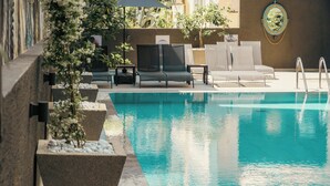 Una piscina con sillas de descanso y macetas.