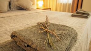 Una cama bien hecha, con una toalla y una pequeña planta.