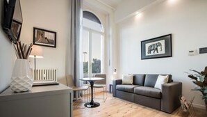 A modern living room with a grey sofa, a round table, and a white radiator. - 7Florence  (Florence)