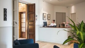A reception area with a wooden reception desk, a receptionist, and a potted plant. - 7Florence  (Florence)