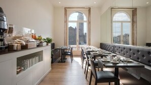 A modern restaurant with a long counter, multiple tables, and a view of the city through large windows. - 7Florence  (Florence)