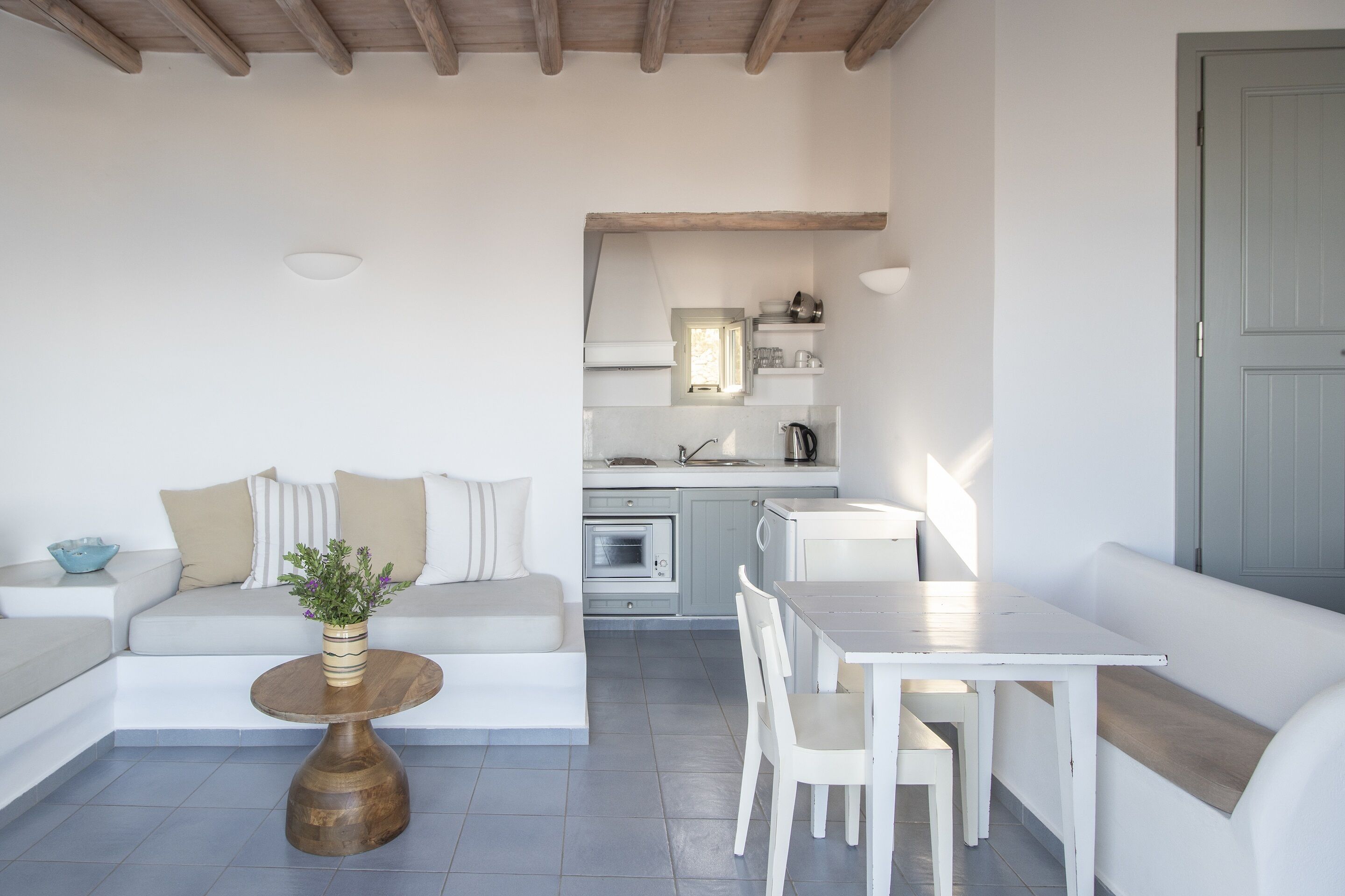 A modern, open-plan living and dining area with a sofa, dining table, and kitchen in the background.