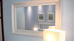 A bathroom with a white vanity, a mirror with a white frame, and two framed pictures on the wall. - Delfino2 Casesicule, Nice Apartment with Balcony, Sand Beach at 70 mt, Wi-Fi (Pozzallo)