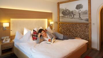A hotel room with a bed, a nightstand with a phone, a wall-mounted picture, and a wooden headboard.