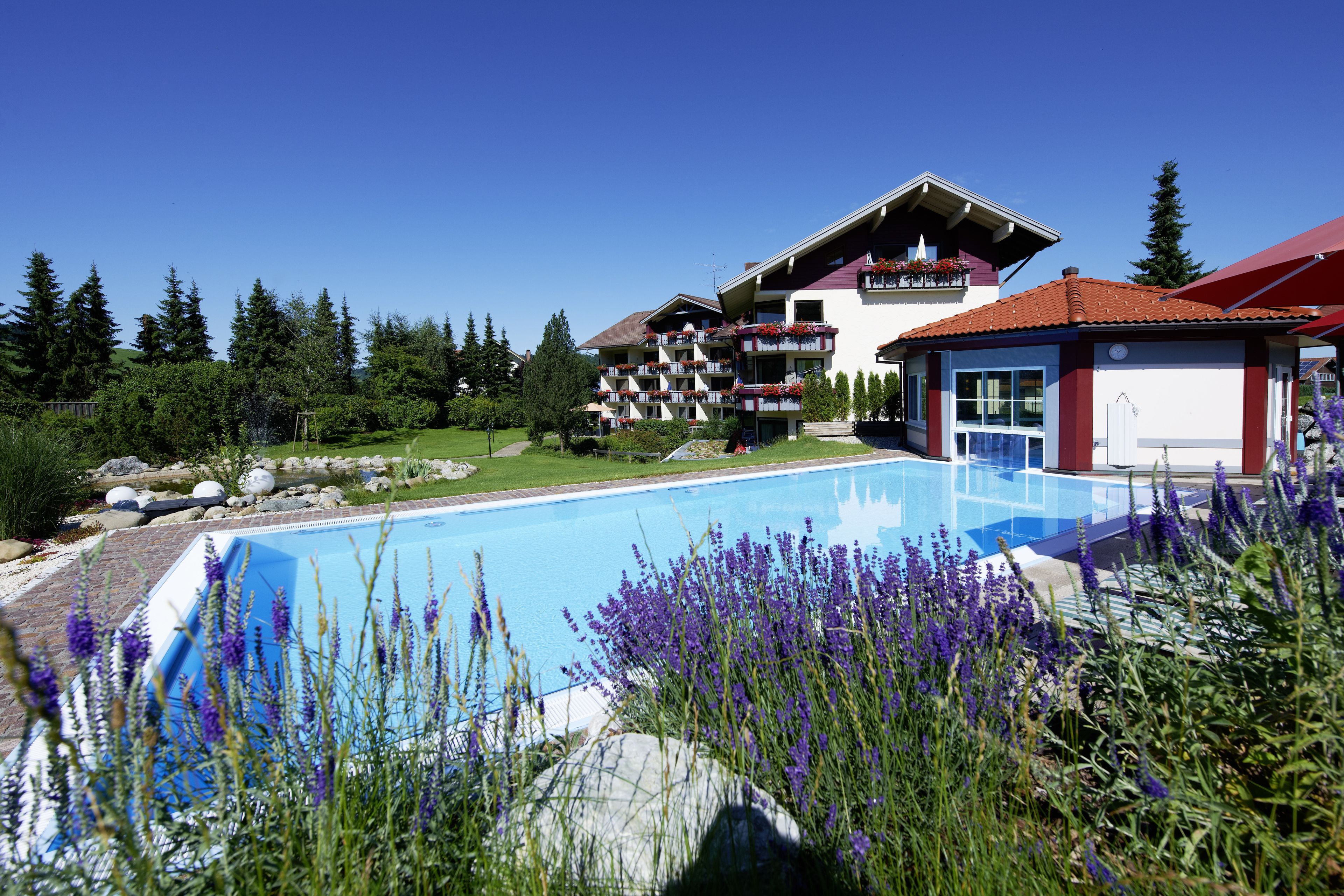 Ein Hotel mit Pool, umgeben von Grünflächen und blauem Himmel.