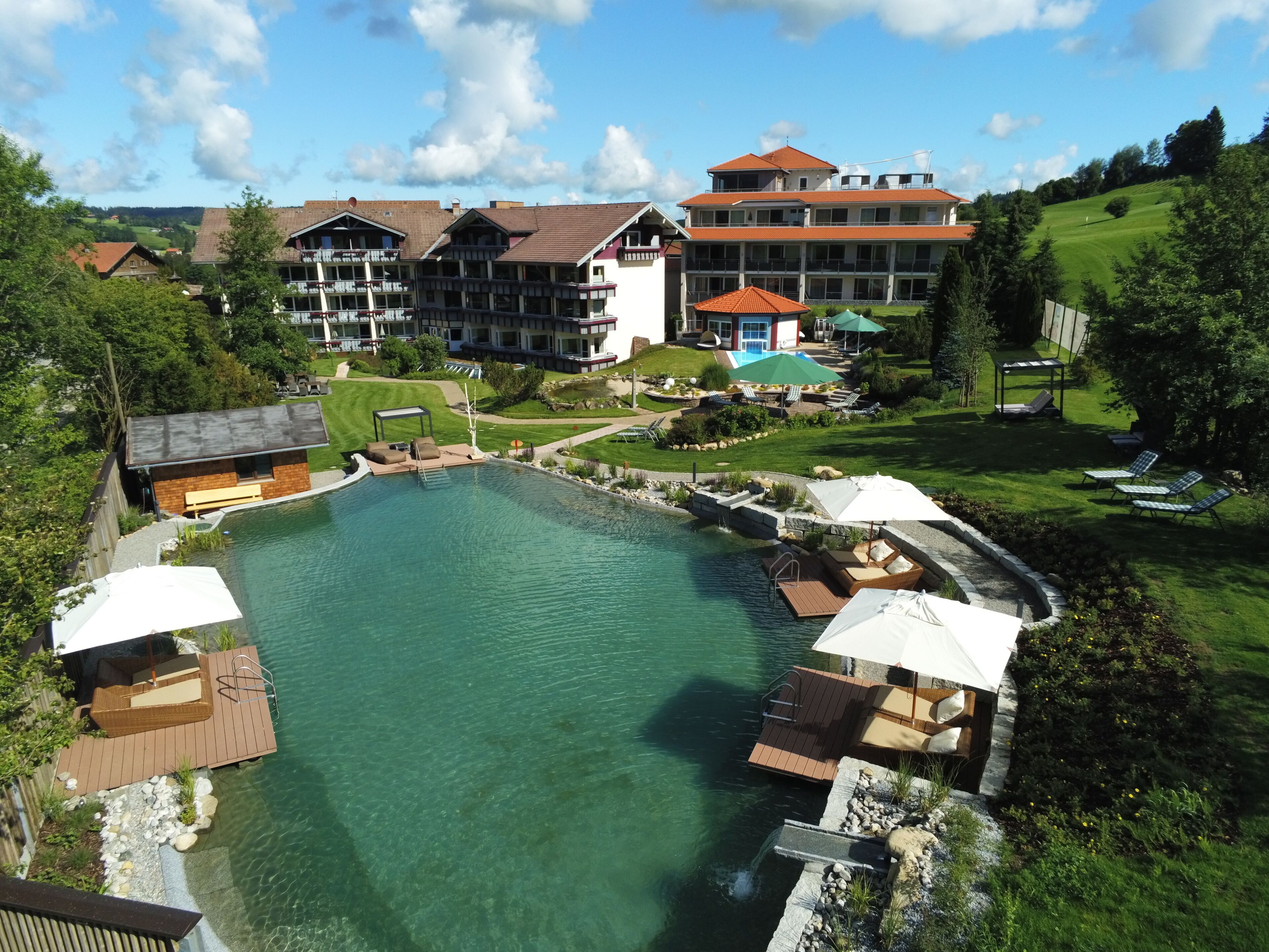 Un resort con piscina, mobiliario exterior y vistas de edificios circundantes.