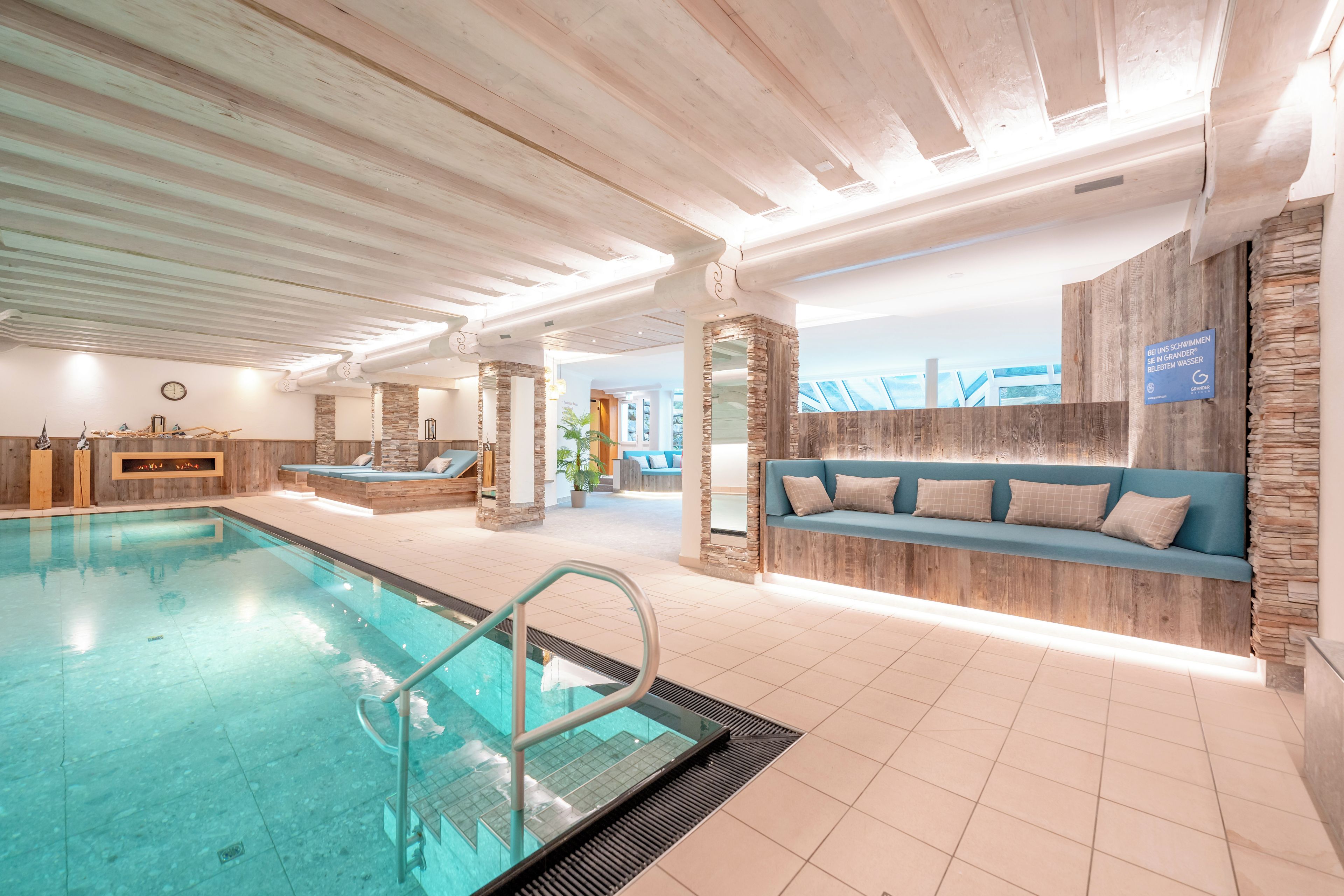 Ein Hallenbad mit Holzbalkendecke, Steinwänden und einem blauen Sofa mit Kissen.