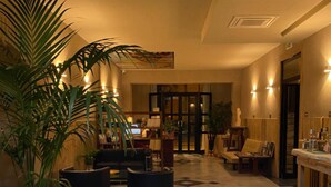 A hotel lobby with a large potted plant, seating area, and a computer displaying the ART HOTEL website. - Art Hotel Pietrasanta (Pietrasanta)