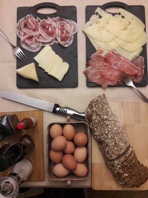 Ein Tisch mit verschiedenen Speisen, darunter Käse, Wurst, Eier und Brot.