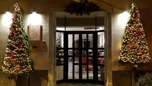 A hotel entrance with a gated door, two Christmas trees on either side, and a sign above the door. - Art Hotel Pietrasanta (Pietrasanta)