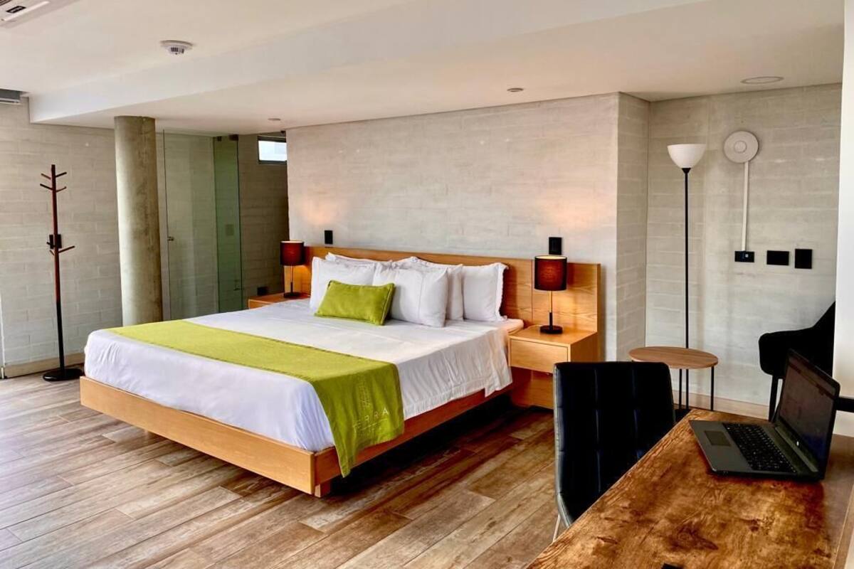 Een moderne hotelkamer met een groot bed, nachtkastjes, een bureau met een laptop en een stoel.