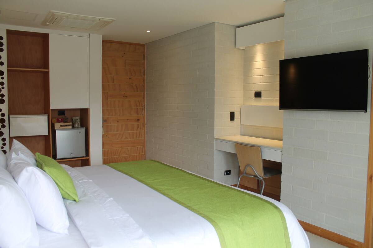 Een hotelkamer met een bed, bureau, televisie en garderobe.