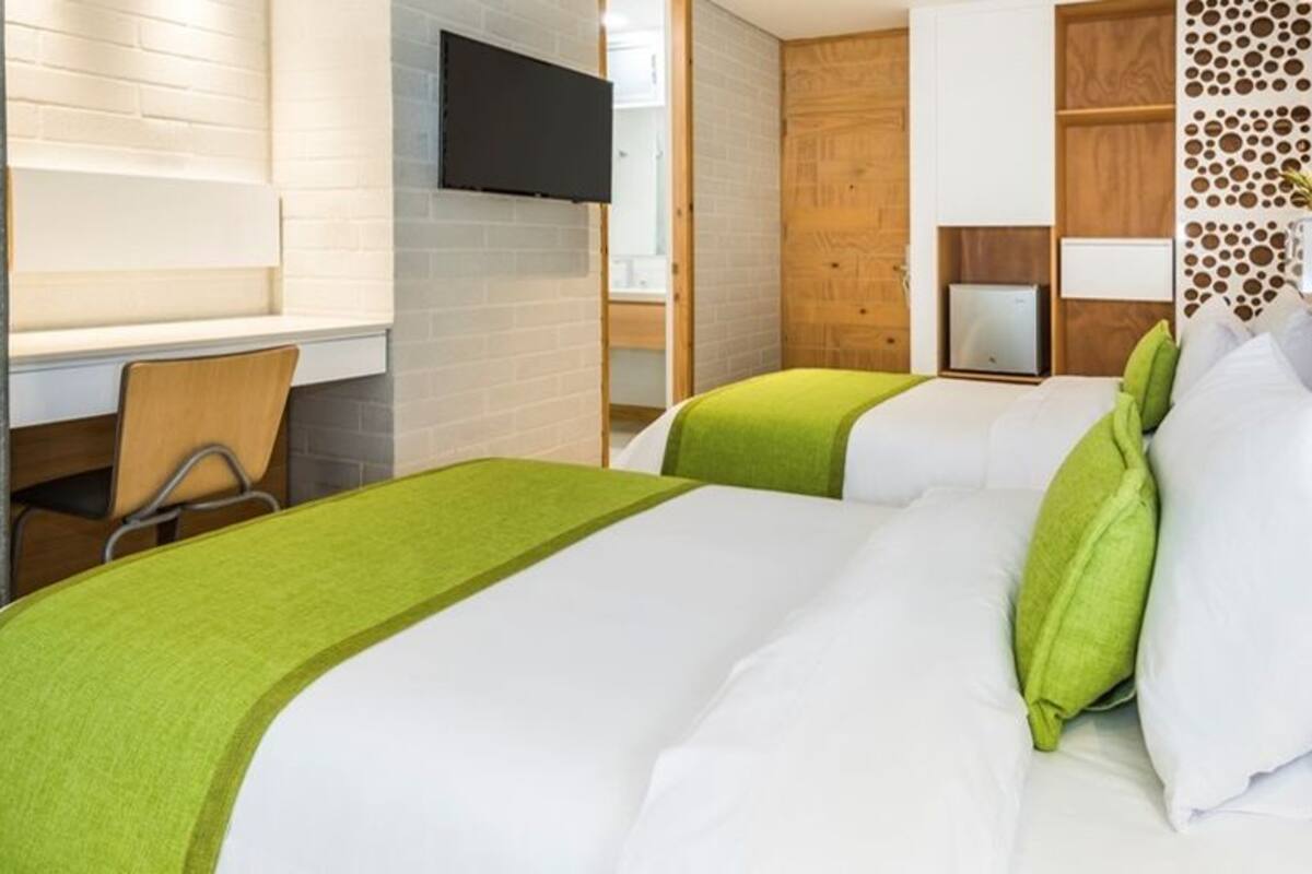 Een hotelkamer met twee bedden, een bureau en een televisie.