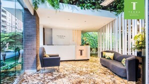 L'espace d'accueil du Terra Biohotel présente un design moderne et comprend un comptoir d'accueil, un coin salon et un mur de verre offrant une vue sur l'extérieur.