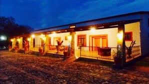 A building with multiple doors and windows, a stone-paved entrance, and outdoor lighting. - Guamúchil Parque Acuático & Cabañas (Etzatlan)
