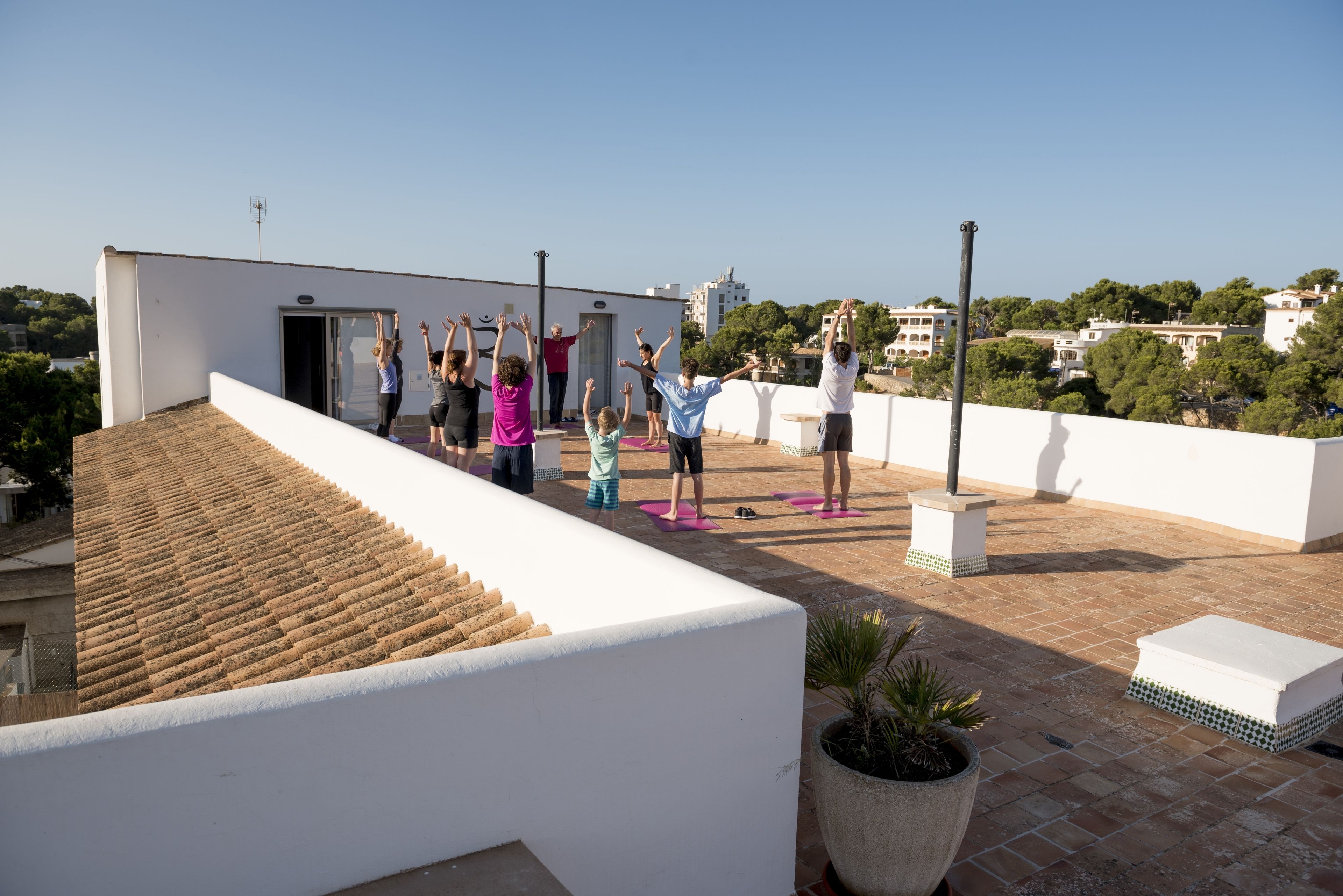 A group of people on a rooftop terrace with a clear view of the surrounding buildings and trees.