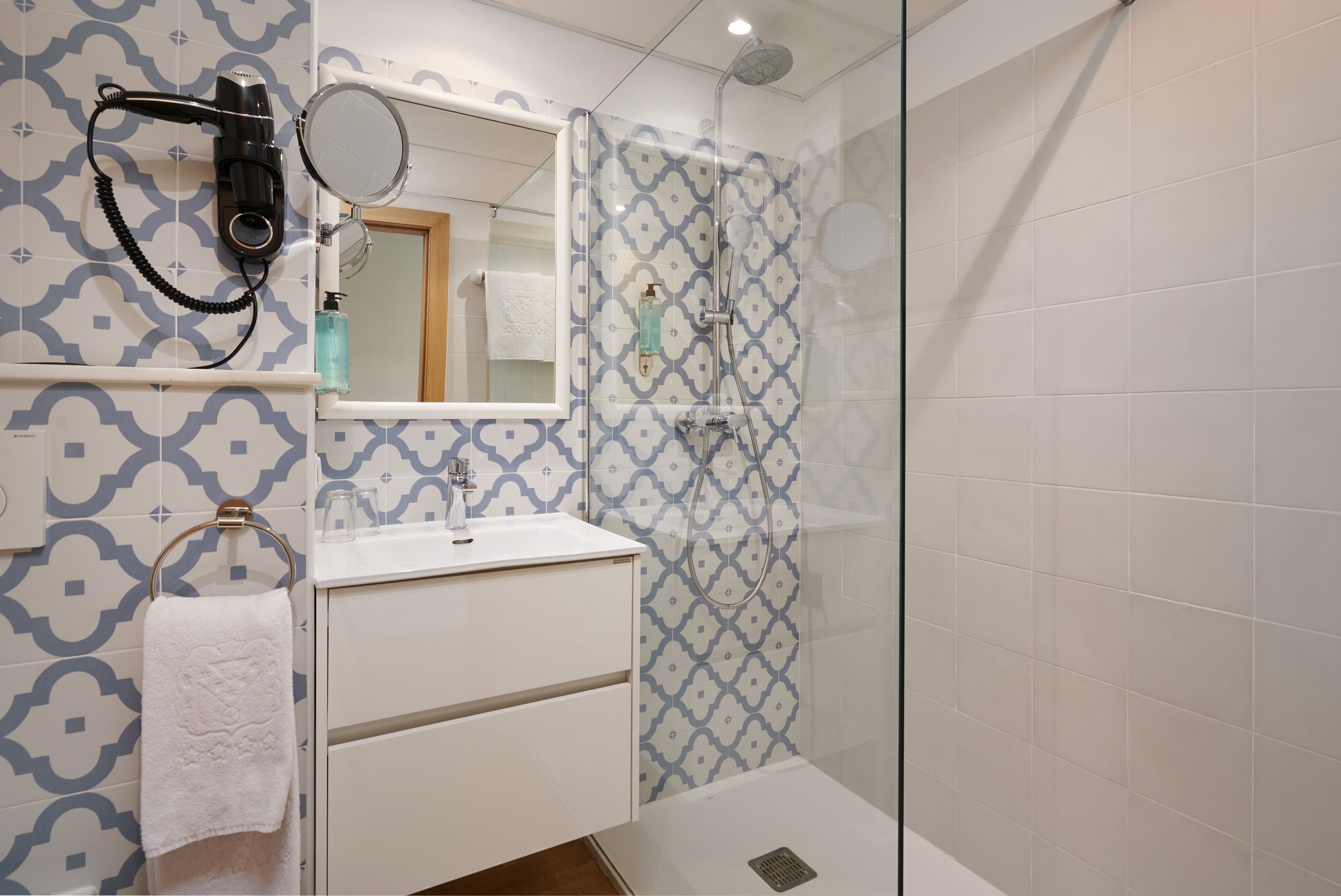 Un baño con pared decorada, un espejo, un lavabo y una ducha.