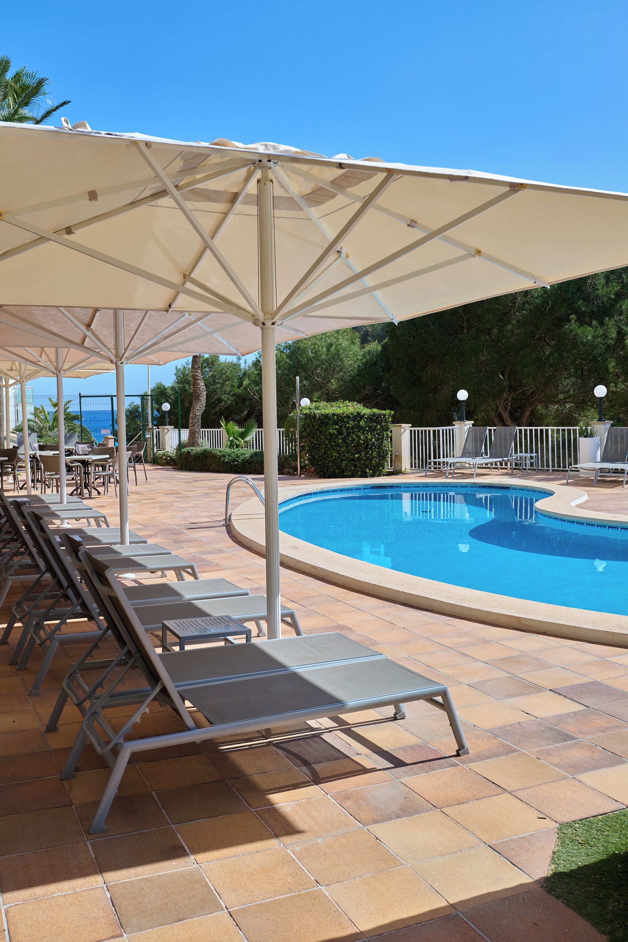 Un espace aménagé au bord de la piscine, avec des chaises longues, une piscine et des parasols.