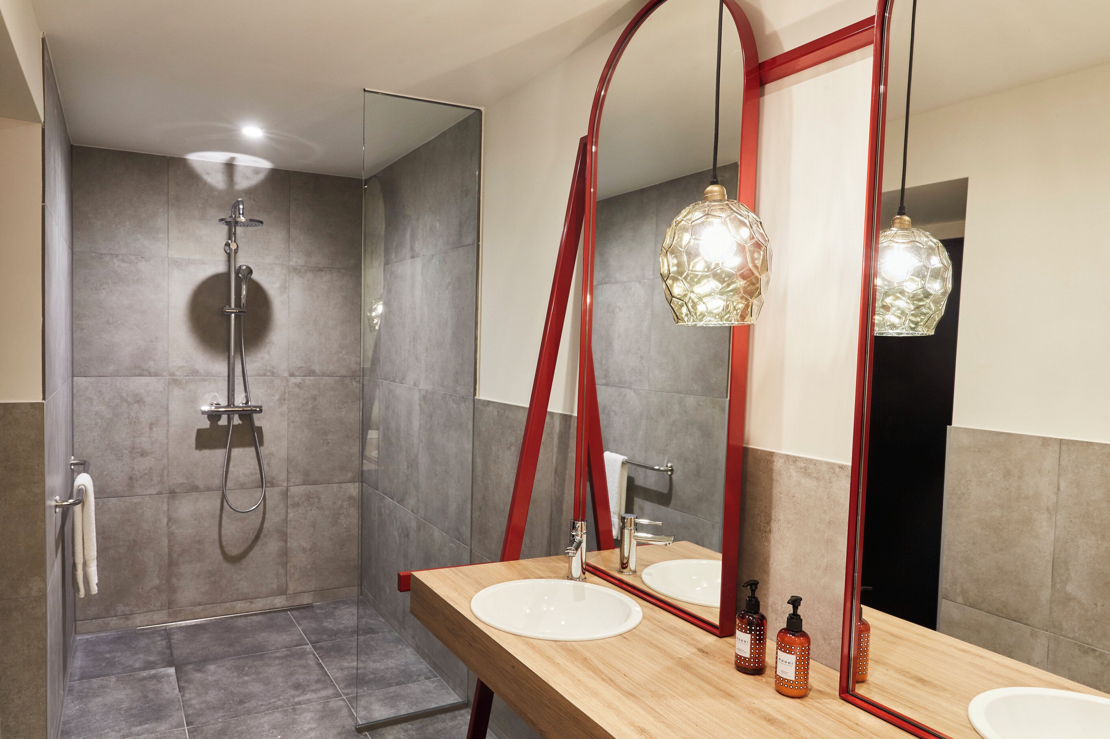 A modern bathroom with a shower, two sinks, and a large mirror.