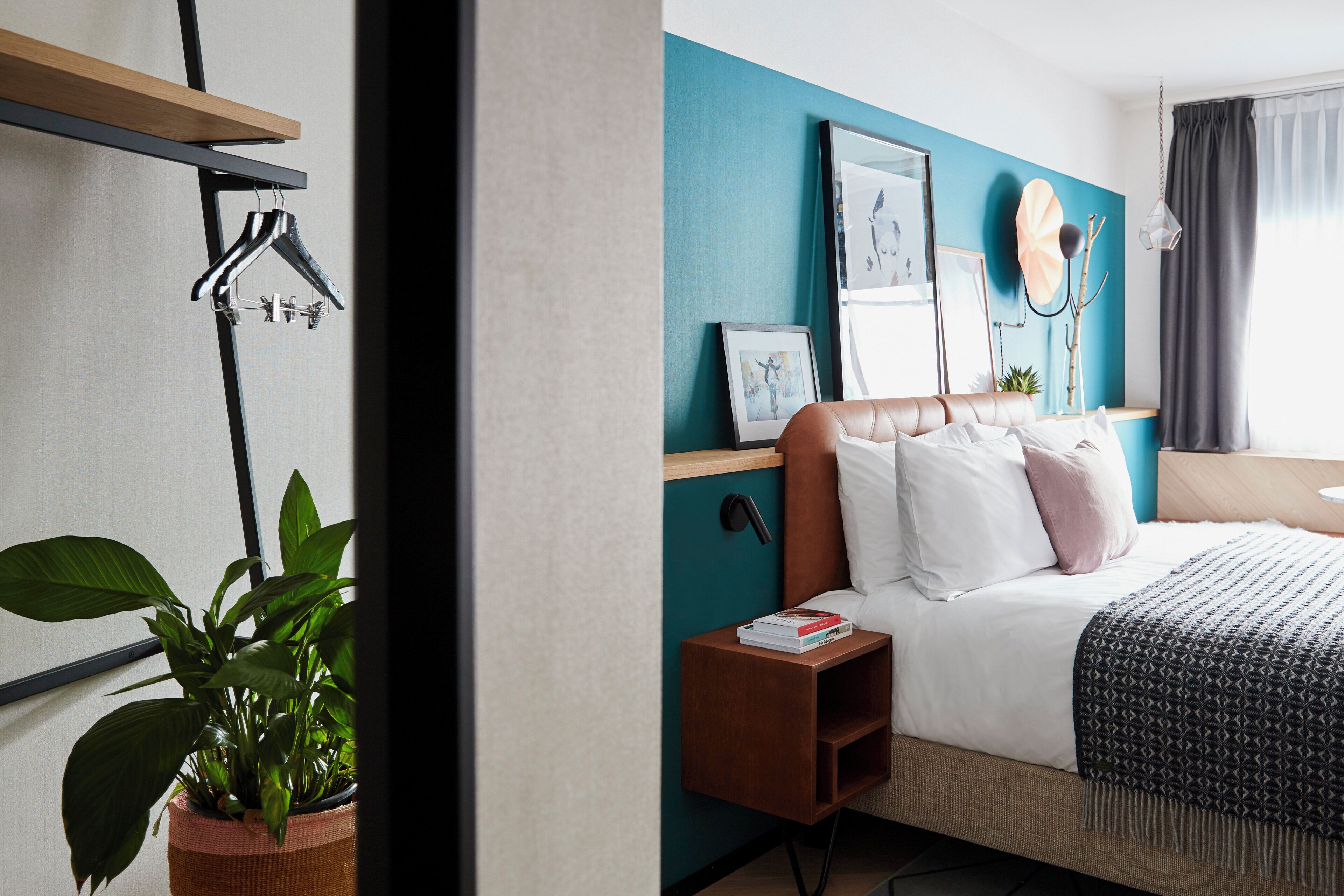 Una habitación de hotel con cama, mesita de noche y lámpara de pared.