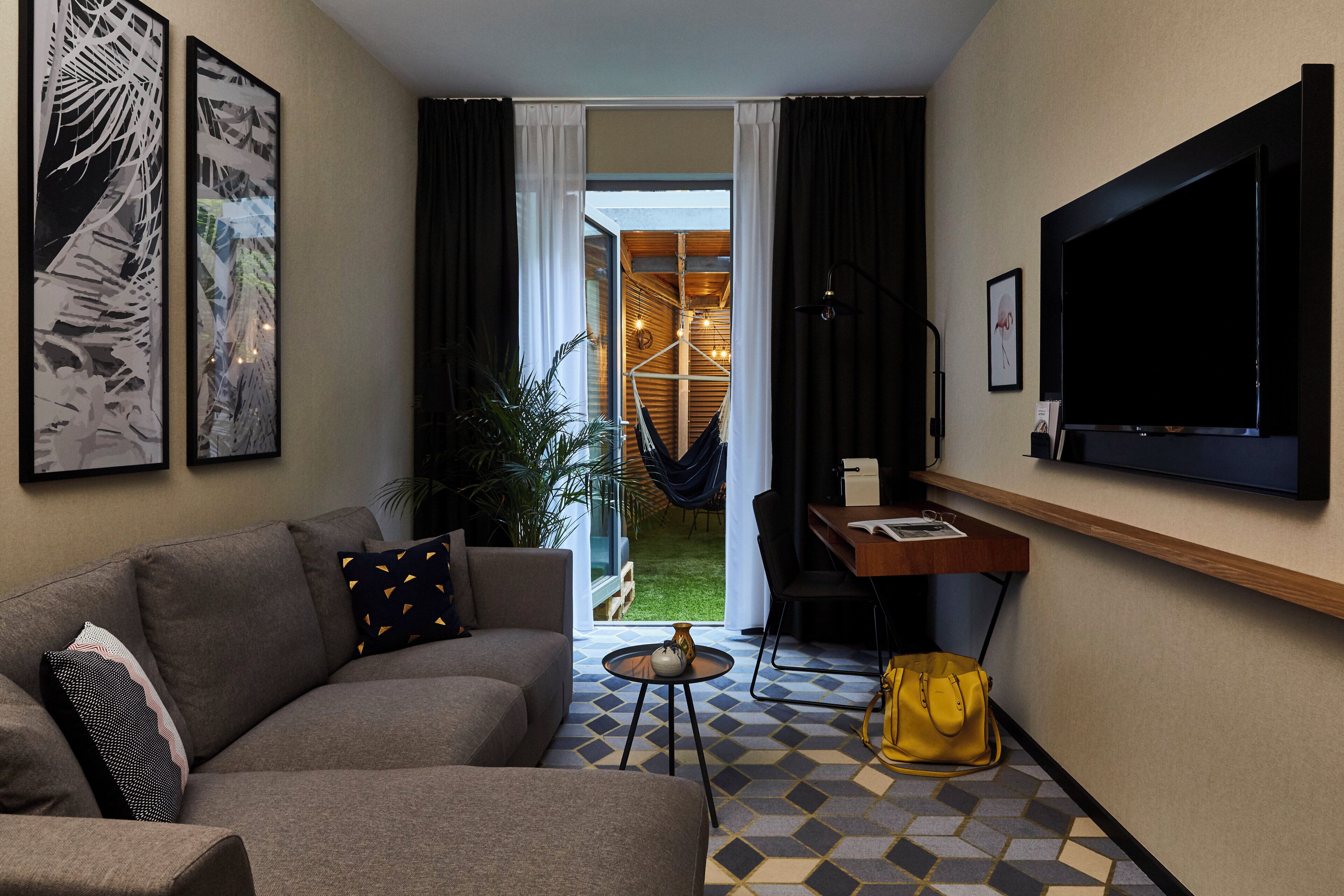 A modern living room with a sofa, a coffee table, a TV, and a dining area with a table and chairs.