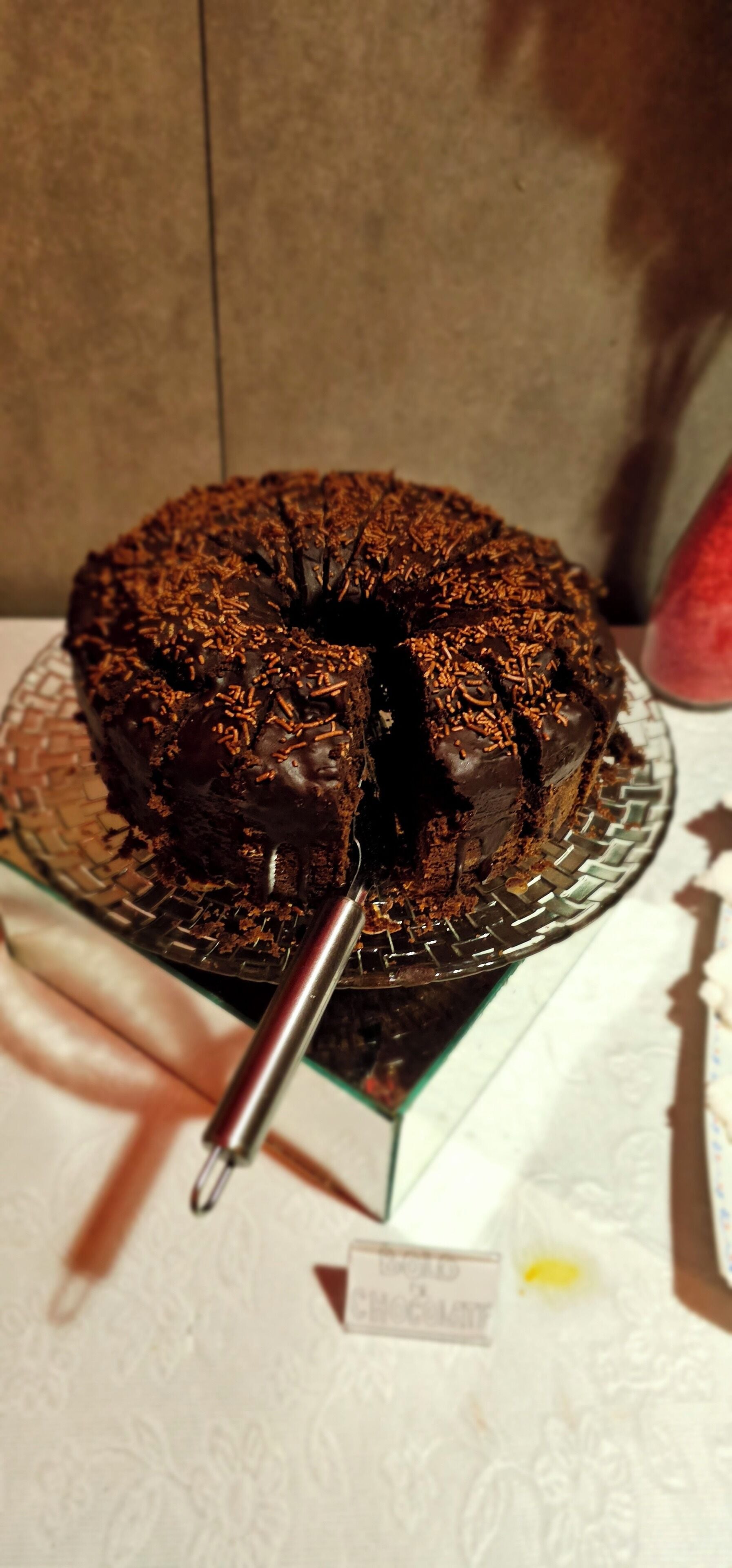 Un pastel de chocolate con chispas sobre un plato de vidrio.