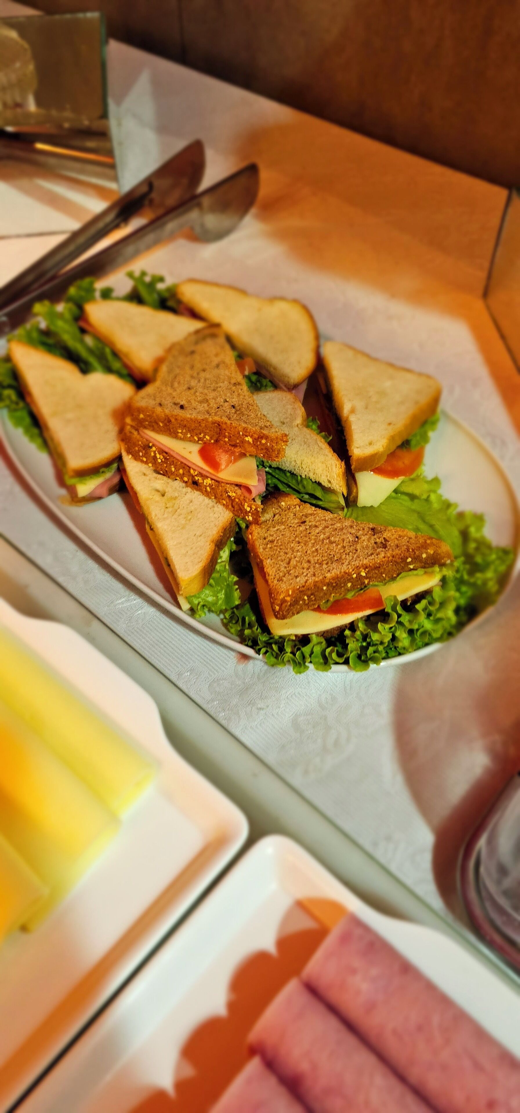 Un plato de sándwiches con lechuga y queso, acompañado de un tenedor y cuchillo sobre una mesa.