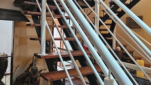 Una escalera de madera con varios niveles, barandillas blancas y techo rústico.