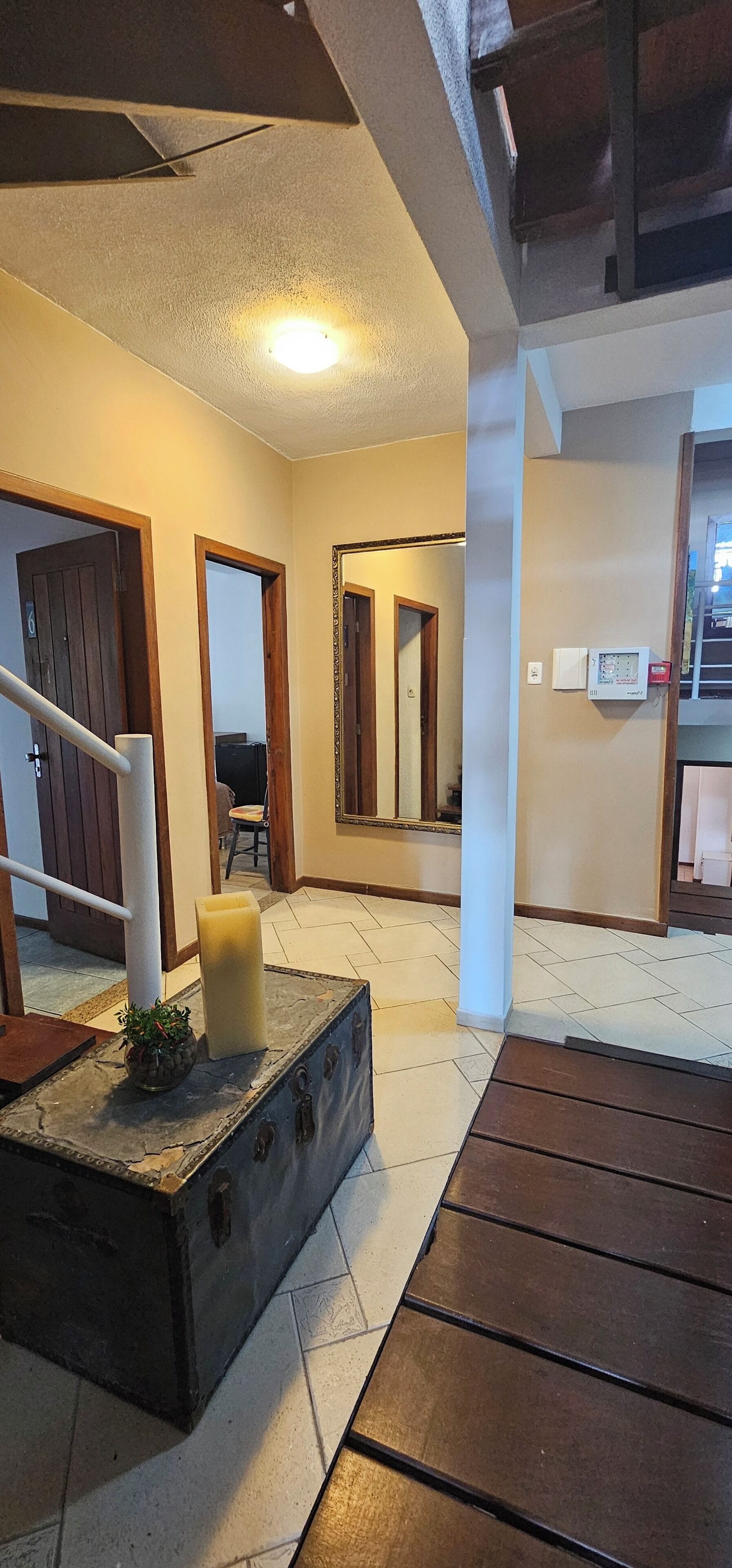 A hallway with a central pillar, a staircase, and a door leading to another room.