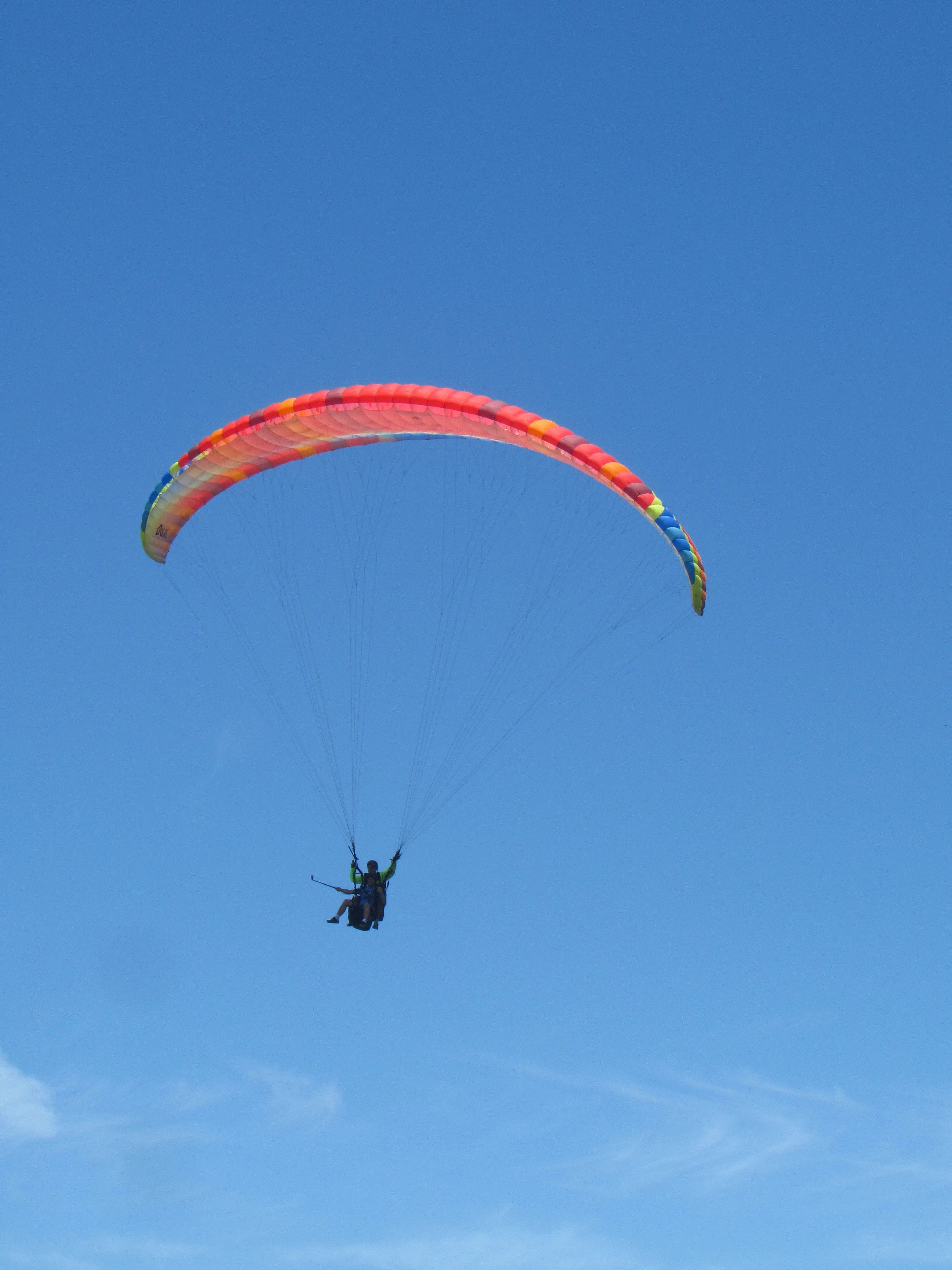 En paraglider med en farverig vinge mod en klar, blå himmel.