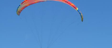 En paraglider med en farverig vinge mod en klar, blå himmel.