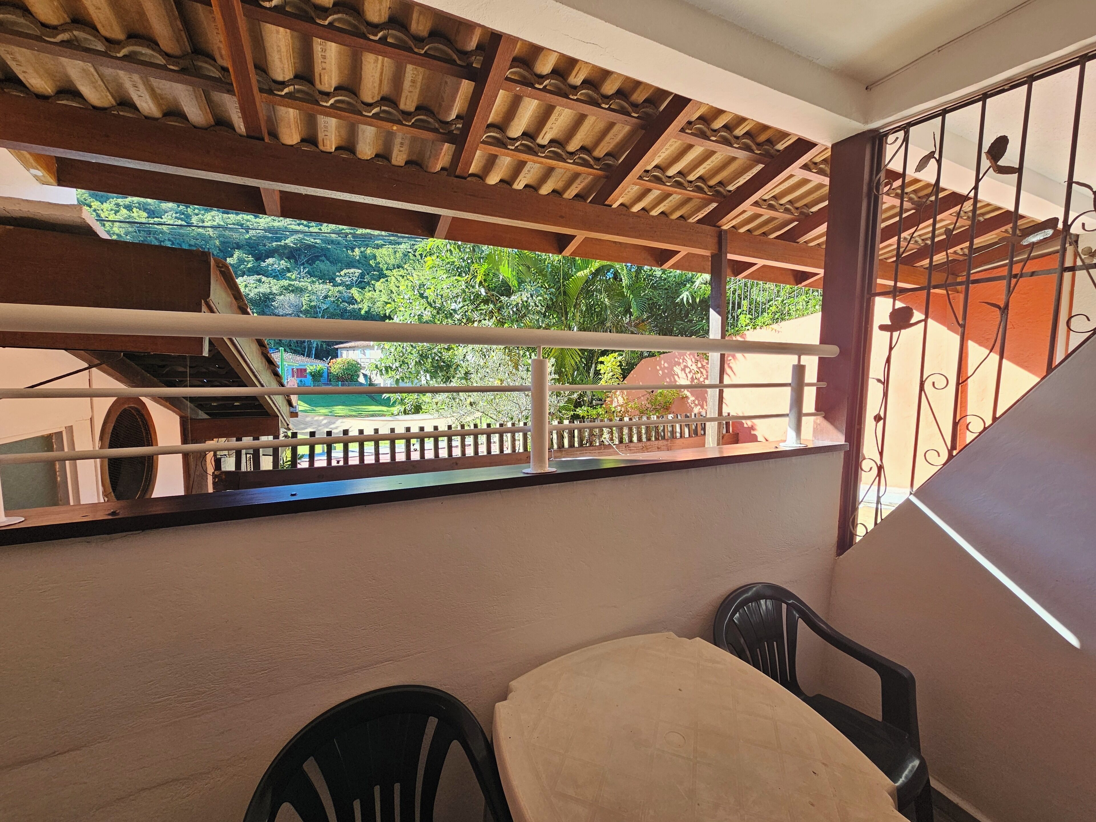 A balcony with a view of greenery and a house in the background.
