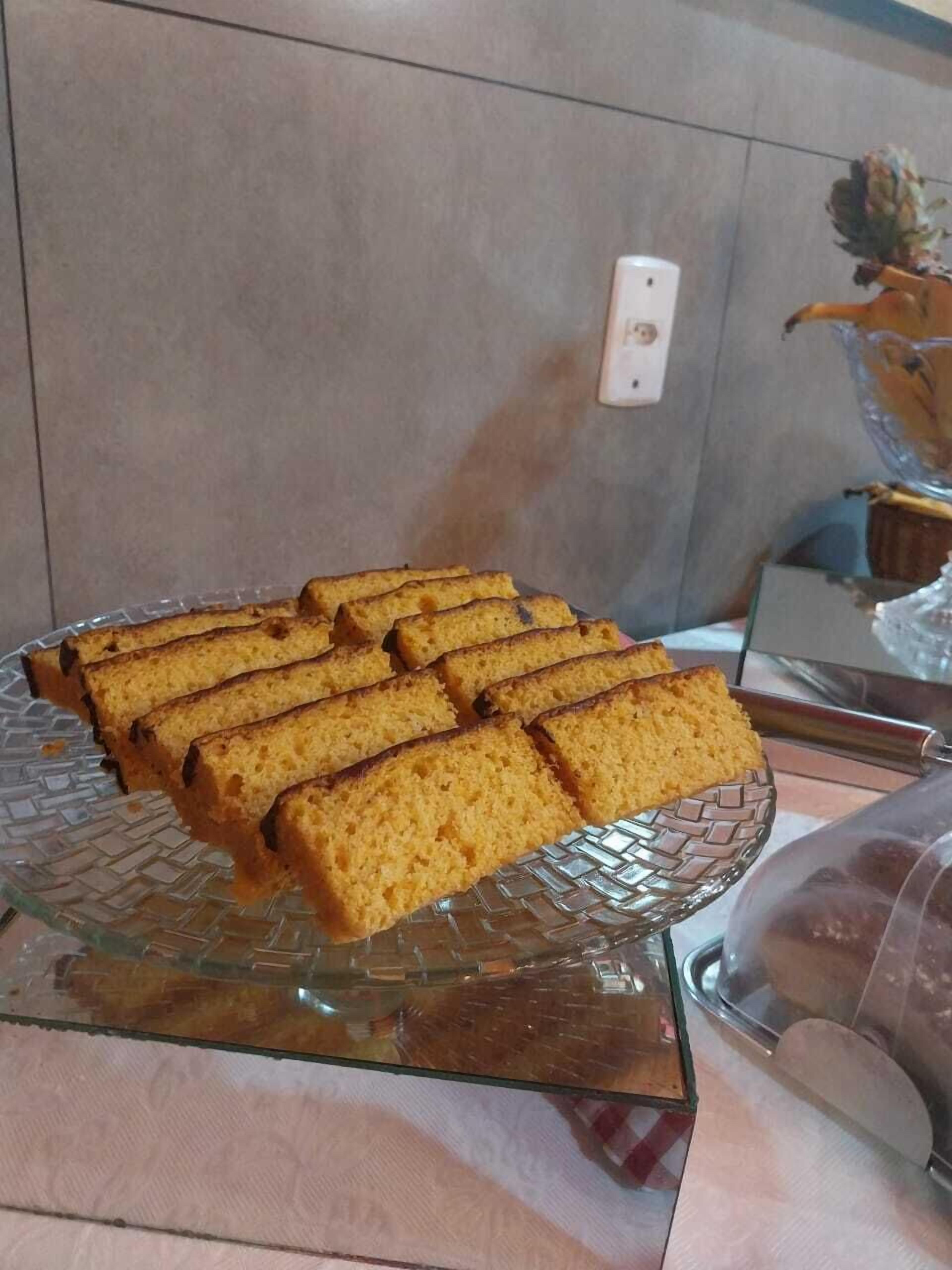 Un présentoir à gâteaux en verre, sur lequel sont disposées plusieurs parts de gâteau, est posé sur une table.