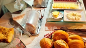 Una mesa de buffet con diversos alimentos, incluyendo pan, bollería y frutas.