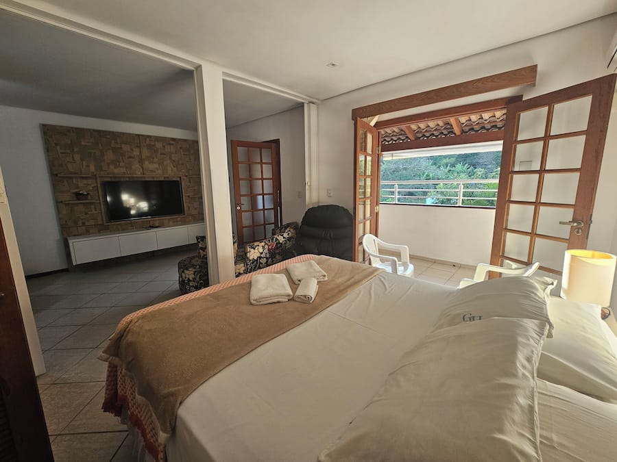 A hotel room with a bed, a TV, a balcony with a view, and a wooden door.