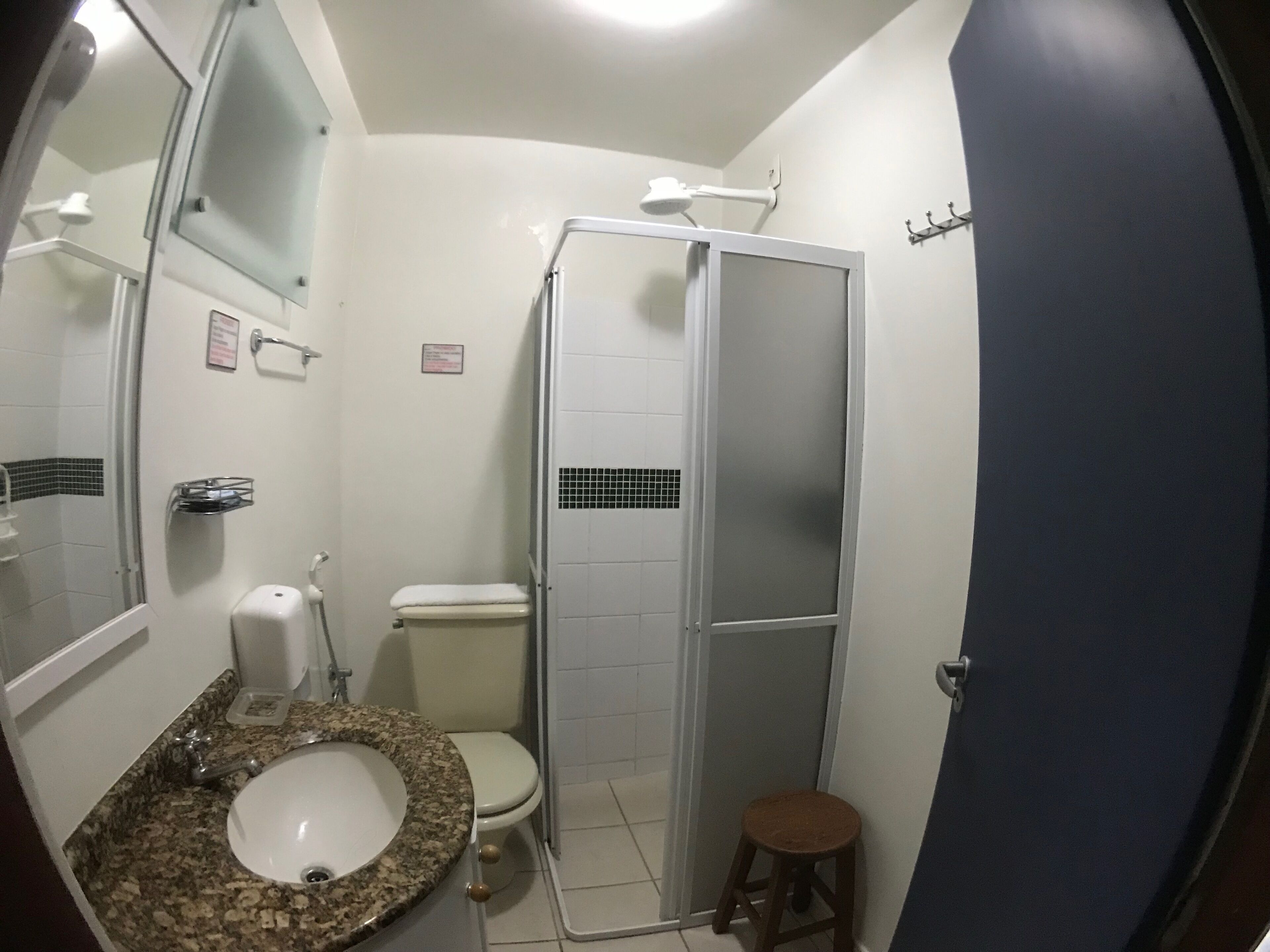 A bathroom with a granite countertop sink, a toilet, a shower stall, and a mirror above the sink.