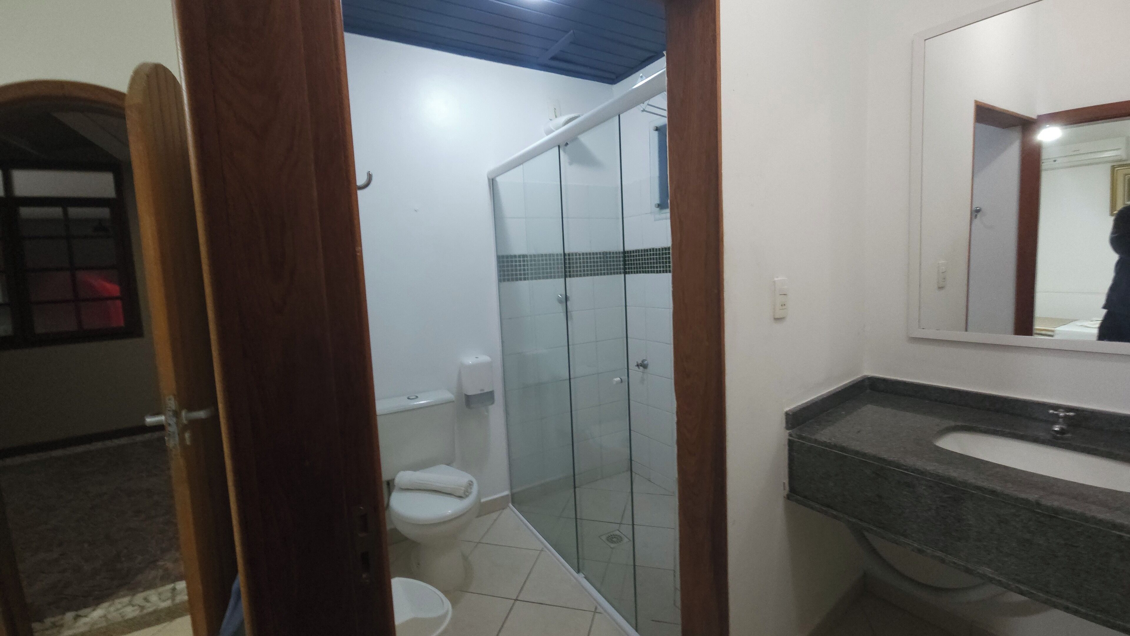 Une salle de bain avec une douche à parois de verre, des toilettes blanches et un lavabo en marbre.