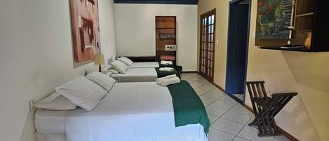 A hotel room with two beds, a ceiling fan, a painting, and a small table.