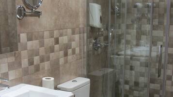 A bathroom with a sink, mirror, toilet, and glass shower enclosure.
