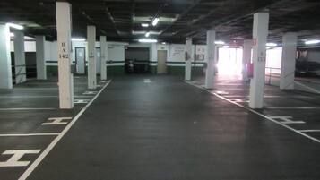 A parking garage with white pillars, marked parking spaces, and directional arrows on the floor.