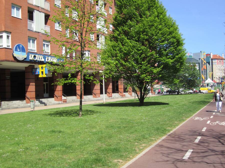 Un hotel con fachada de ladrillo rojo, un letrero y un árbol en la parte delantera.