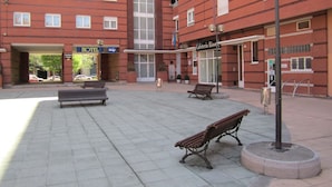 A courtyard with benches, a hotel, and a cafe. - Hotel Bahía (Gijon)