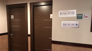 A hotel hallway with two doors, each marked with room numbers 111-128 and 101-110. A prohibition sign for smoking is also visible. - Hotel Bahía (Gijon)