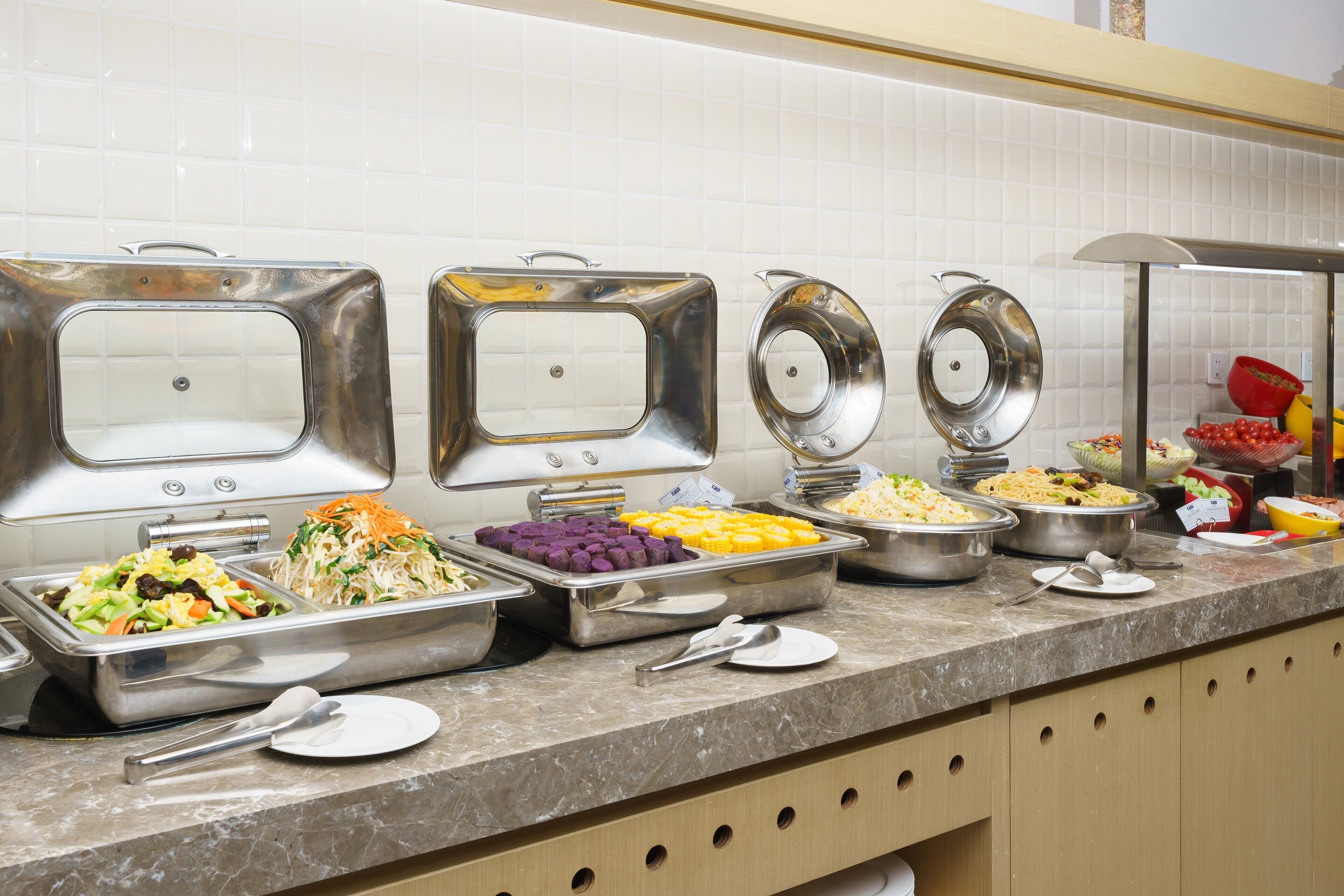 A buffet line with various food options in metal serving dishes.
